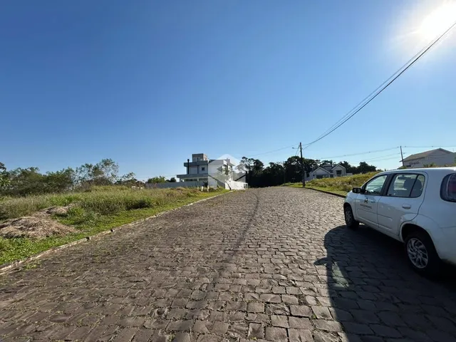 Uma rua pavimentada leva a uma casa branca no horizonte.