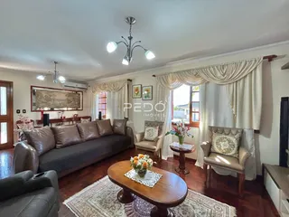 Sala de estar com sofá e poltronas em madeira no interior da residência.