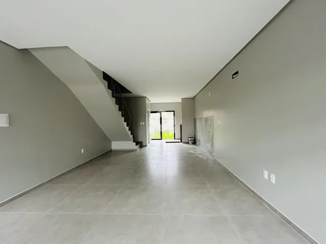 Corredor interno de uma residência com paredes cinzas e piso claro.