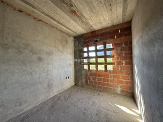 A parede interna da construção exibe tijolos aparentes e paredes de concreto cru.