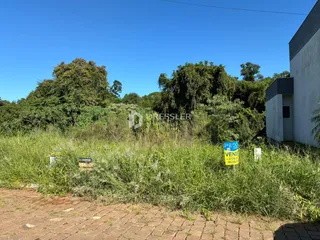 Fachada de uma residência com vegetação densa ao fundo.