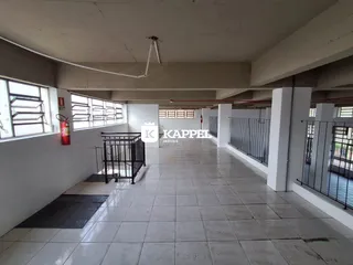 Corredor longo com piso de cerâmica e paredes brancas.