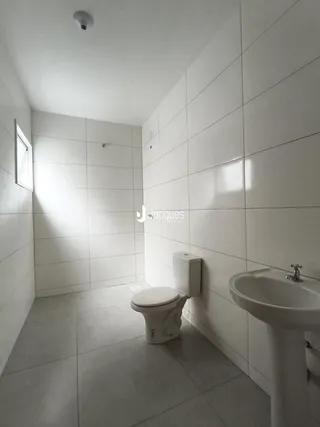 Banheiro com revestimento cerâmico branco e piso claro.