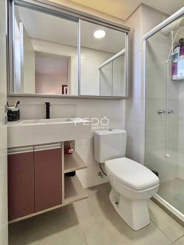 Foto de um banheiro com louças sanitárias brancas e revestimento de azulejos.