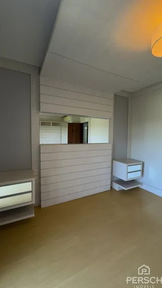 Uma sala de estar com paredes claras e piso de madeira clara.