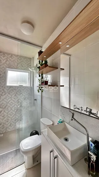 Foto de um banheiro moderno com revestimento cerâmico e box de vidro.