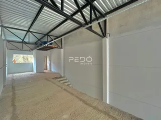 Corredor interno de uma propriedade com estrutura de telhado metálico exposta.