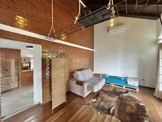 Sala de estar com paredes de tijolo aparente e piso de madeira.