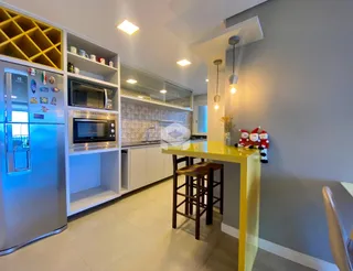 Vista da cozinha moderna com armários brancos e bancada amarela.