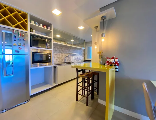 Vista da cozinha moderna com armários brancos e bancada amarela.
