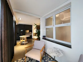 Sala de estar com grande janela e cortinas escuras.