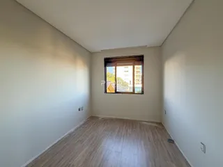 Vista interna de um ambiente com piso de madeira e paredes brancas.