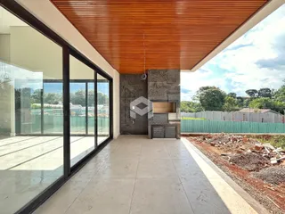 Vista de uma área externa com piso de cerâmica e parede de concreto em uma residência.