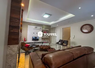 Sala de estar com sofá marrom e televisão na parede.