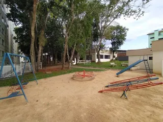 Área externa com árvores e estrutura de playground em terra.
