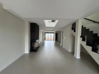 Hall de entrada longo com paredes brancas e piso claro.