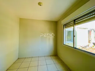 Ambiente interno de uma sala com piso de cerâmica clara e paredes bege.
