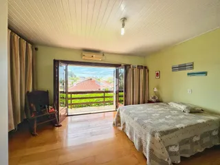 Quarto com piso de madeira e vista para o exterior.