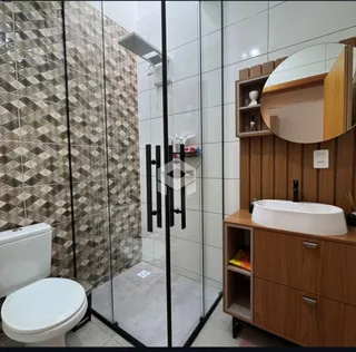 Interior de um banheiro com box de vidro e vaso sanitário branco.