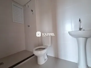 Foto interna de um banheiro com revestimento branco e louças brancas.