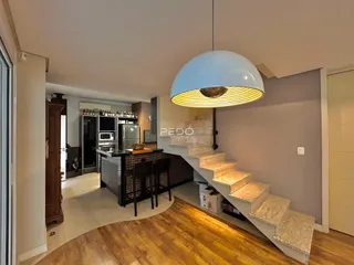 Ambiente interno de uma sala de estar com cozinha e escadaria em Lajeado.