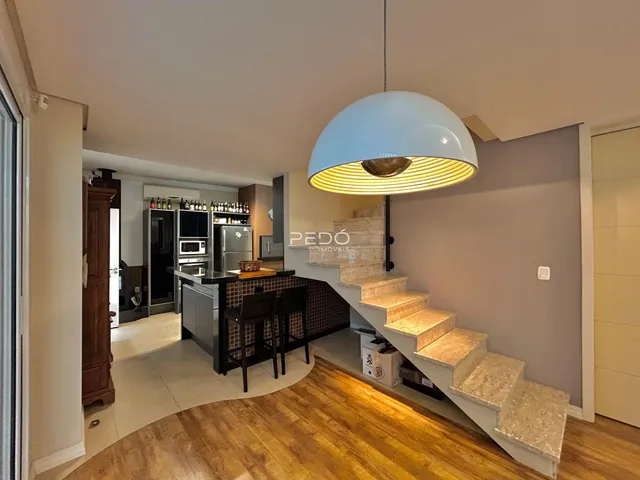 Ambiente interno de uma sala de estar com cozinha e escadaria em Lajeado.