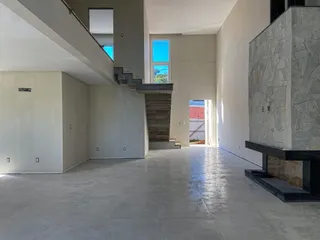 Vista interna de um hall com escadaria e parede de pedra em um imóvel.