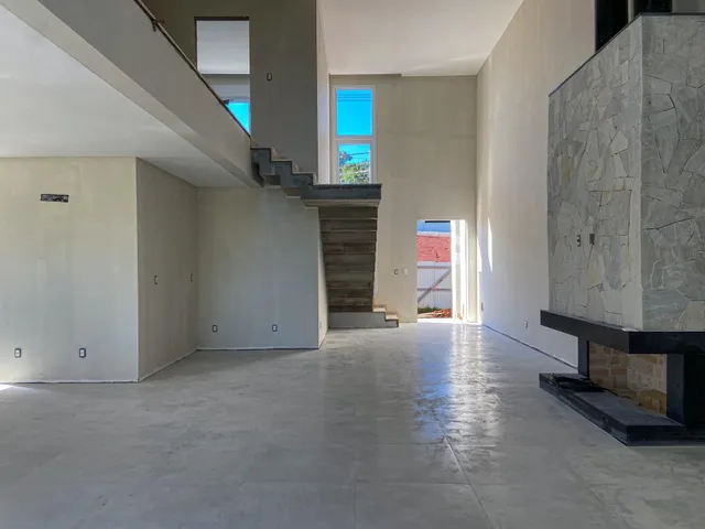 Vista interna de um hall com escadaria e parede de pedra em um imóvel.