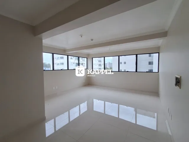 Esta é uma sala ampla com piso claro e grandes janelas.