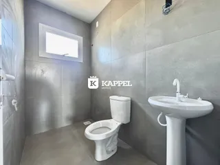 Banheiro com vaso sanitário e pia brancos em um ambiente moderno.