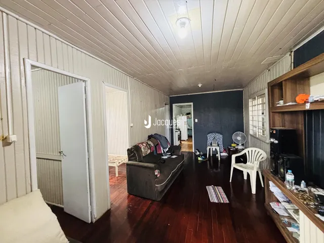 Sala de estar com piso de madeira e paredes brancas em um imóvel no Brasil.