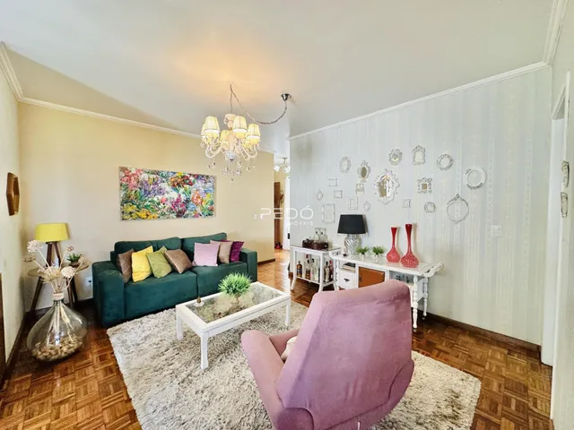 Sala de estar com sofá verde e tapete claro em um imóvel no Brasil.