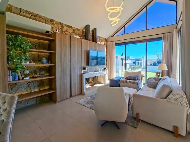 Sala de estar moderna com parede de pedra e grande janela com vista para o exterior.