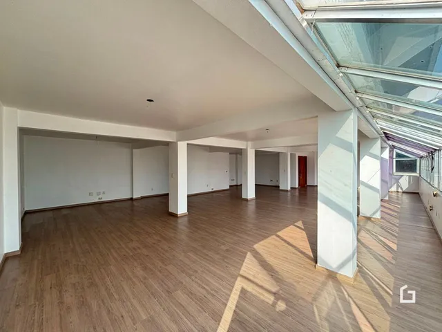 Ambiente interno amplo com piso de madeira e teto alto.