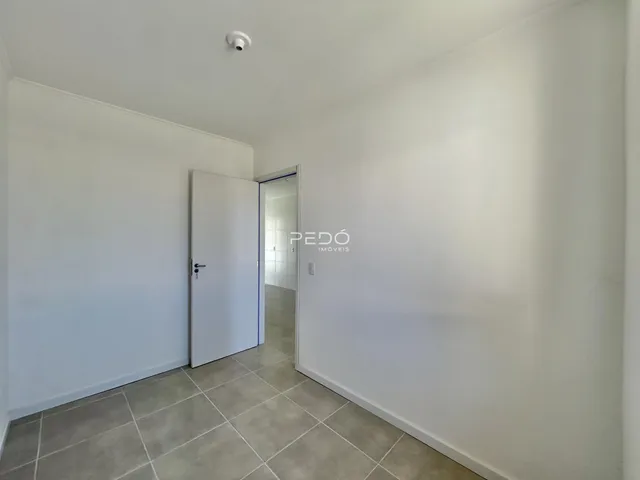 Corredor com paredes brancas e piso de cerâmica cinza claro.