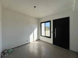 Vista interna de um cômodo amplo com paredes brancas e piso cinza.