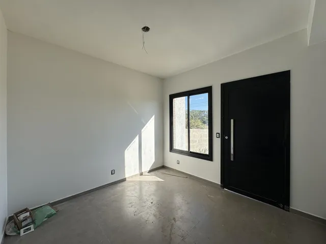 Vista interna de um cômodo amplo com paredes brancas e piso cinza.