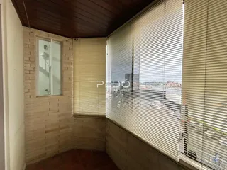 Interior de uma sala com parede de tijolos e janela com persianas.