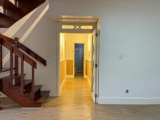 Hall de entrada com escada de madeira e piso de madeira clara.
