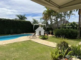 Vista externa de uma propriedade com piscina e jardim.