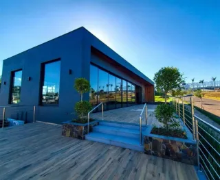 Fachada moderna de uma residência com deck de madeira e paisagem ao fundo.