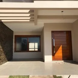 Fachada externa de uma residência com porta de madeira e piso claro.