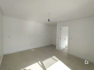 Ambiente interno de uma sala vazia com paredes brancas.