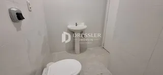 Banheiro com revestimento cerâmico branco e louças sanitárias instaladas.