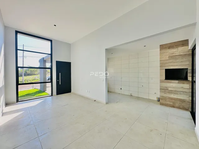 Sala de estar ampla com piso de cerâmica clara e porta de vidro.