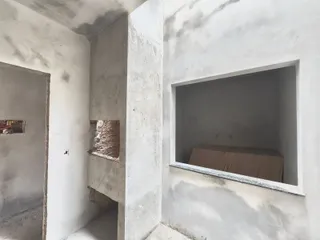 Foto de uma parede interna com acabamento de concreto aparente e estrutura bruta.