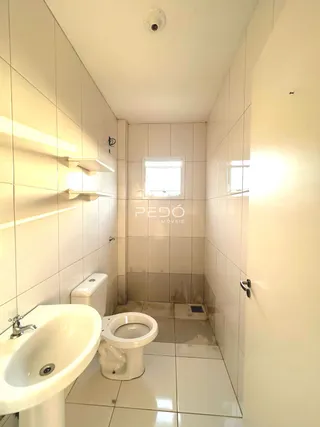 Interior de um banheiro com azulejos brancos e vaso sanitário.