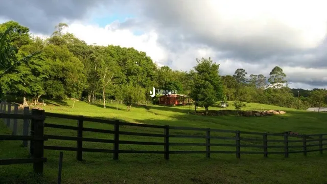 Vista de um campo gramado com cerca de madeira.