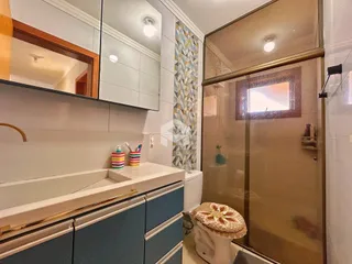 Interior de um banheiro com bancada e box de vidro.