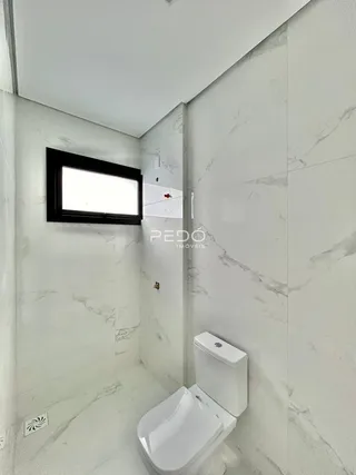 Foto de um banheiro com revestimento branco e vaso sanitário.